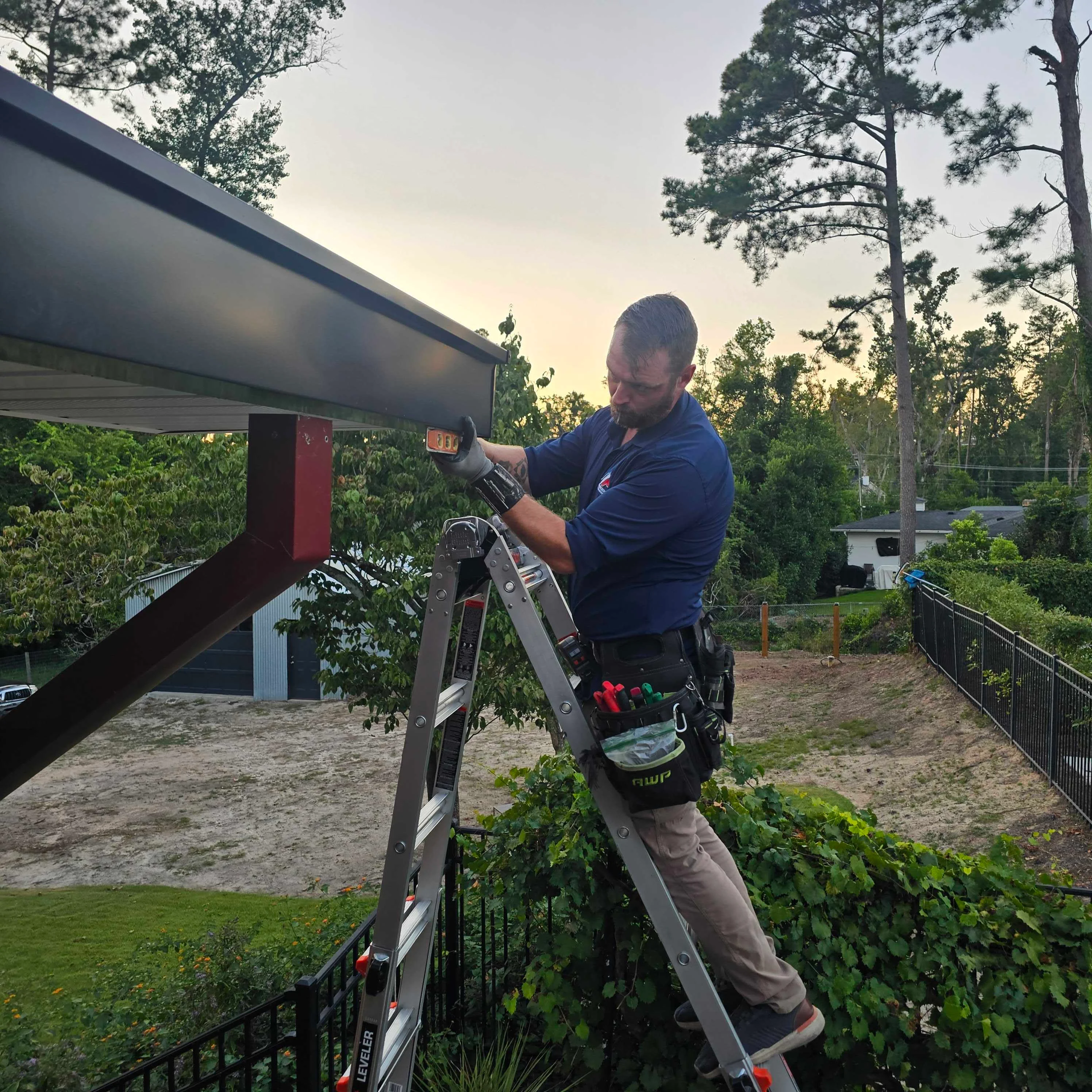 Technician installing metal gutters on residential roof with ladder and tools