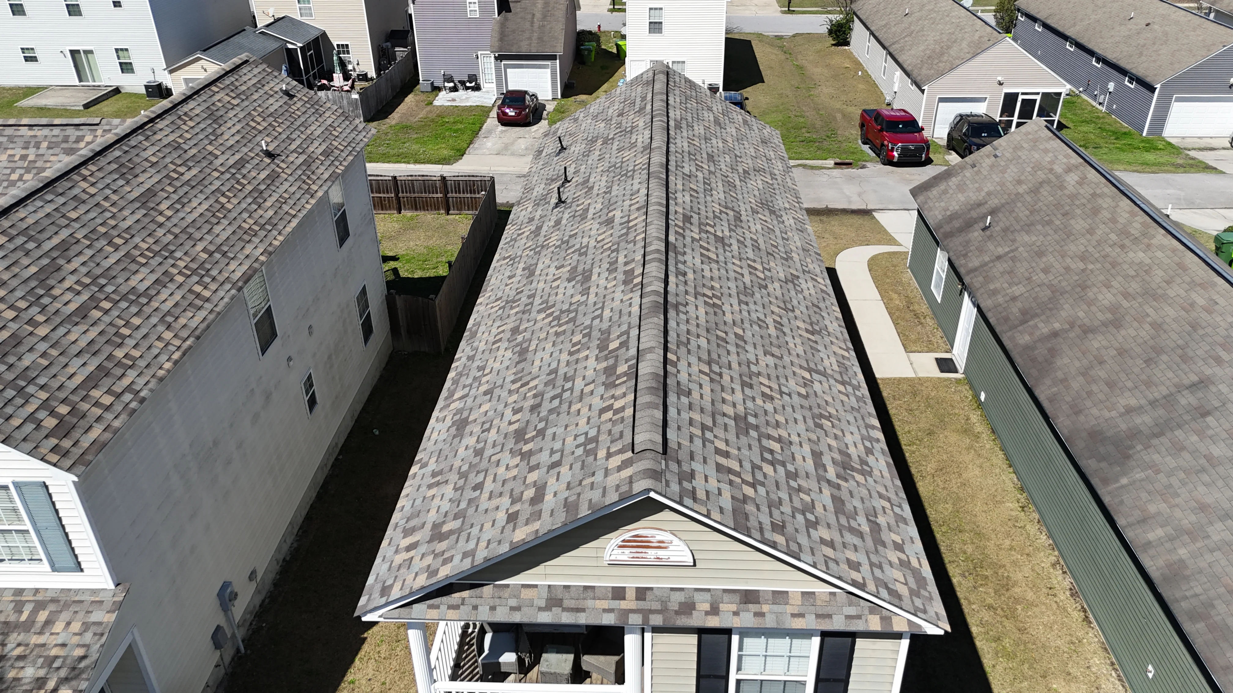 Aerial view of newly installed gray architectural shingle roof with ridge cap and gable peak flashing
