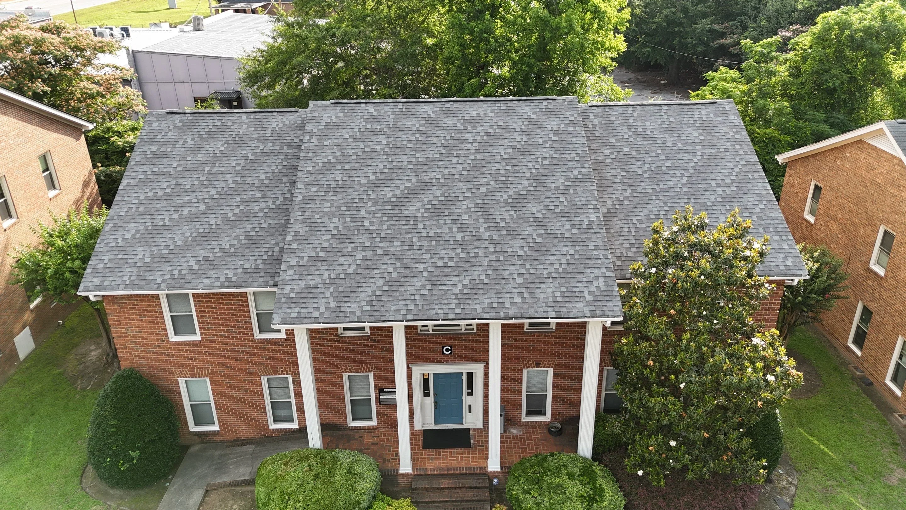 Gray asphalt shingle roof on brick colonial home with white trim and columns