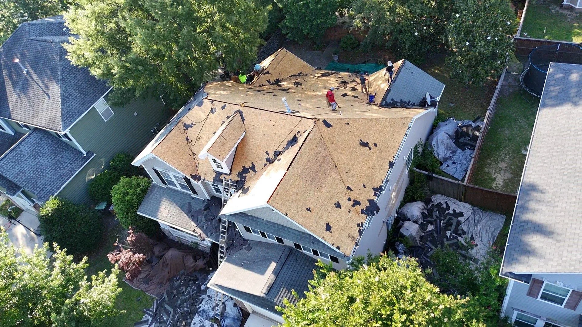 Aerial view of residential roof with new asphalt shingles and white trim during installation