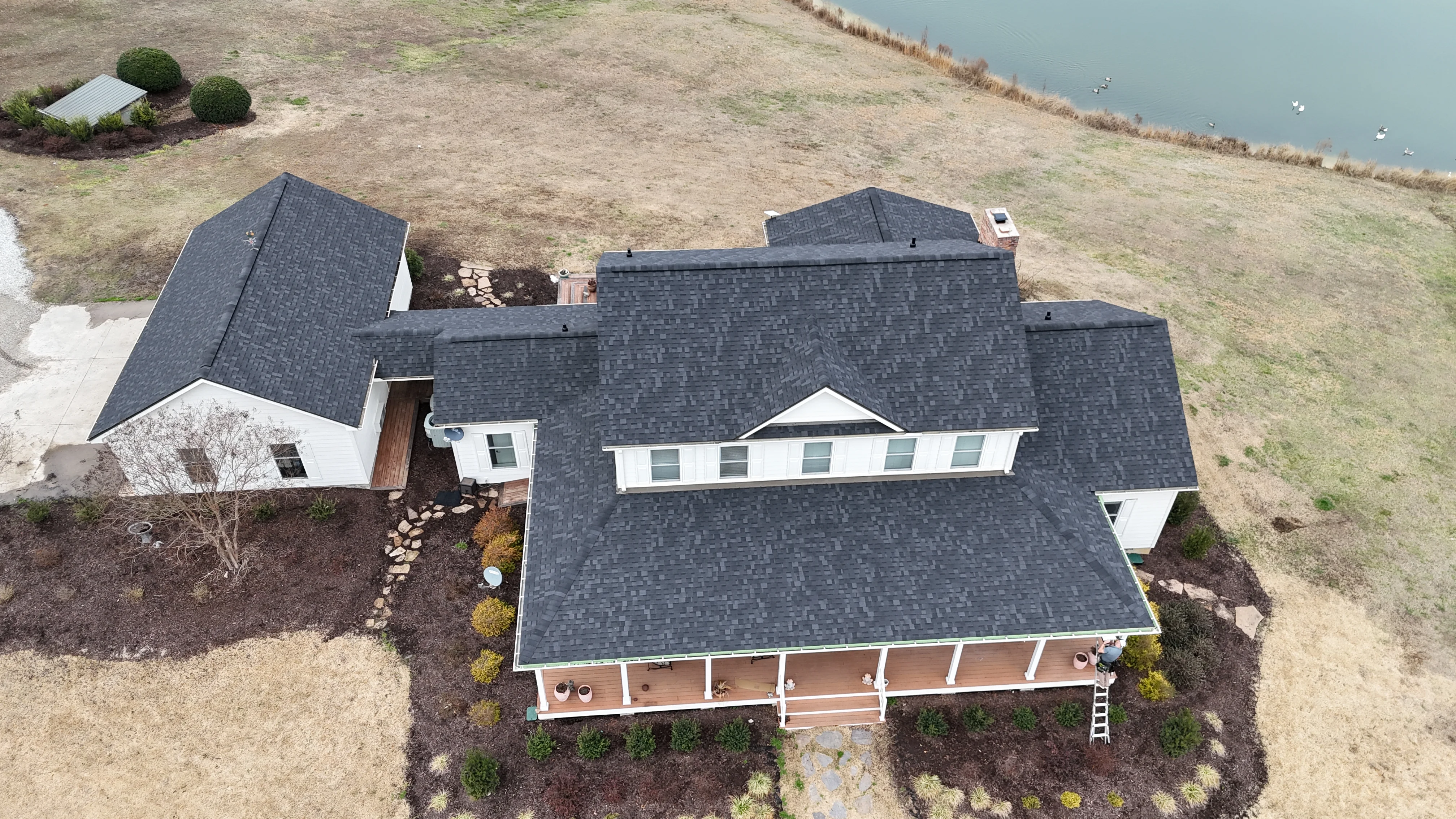 Dark gray asphalt shingle roof installation on multi-section residential home with white trim