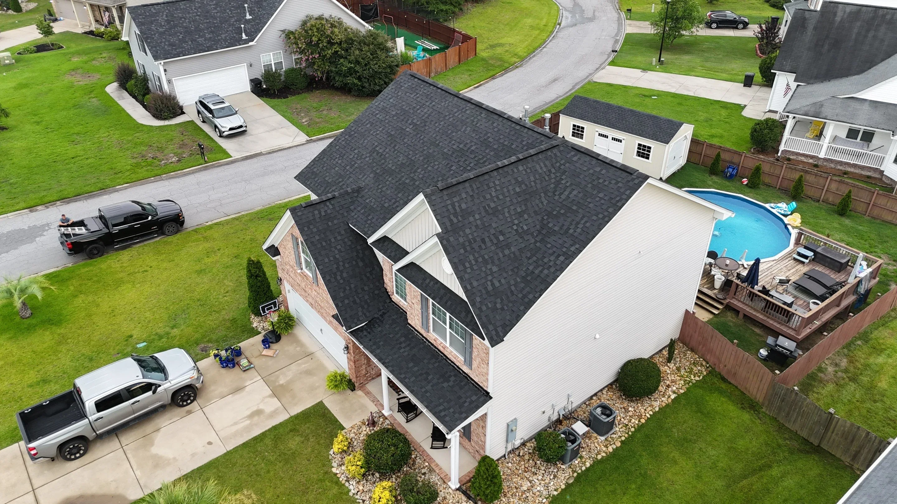 Two-story home with new charcoal architectural shingle roof installation, brick and vinyl siding