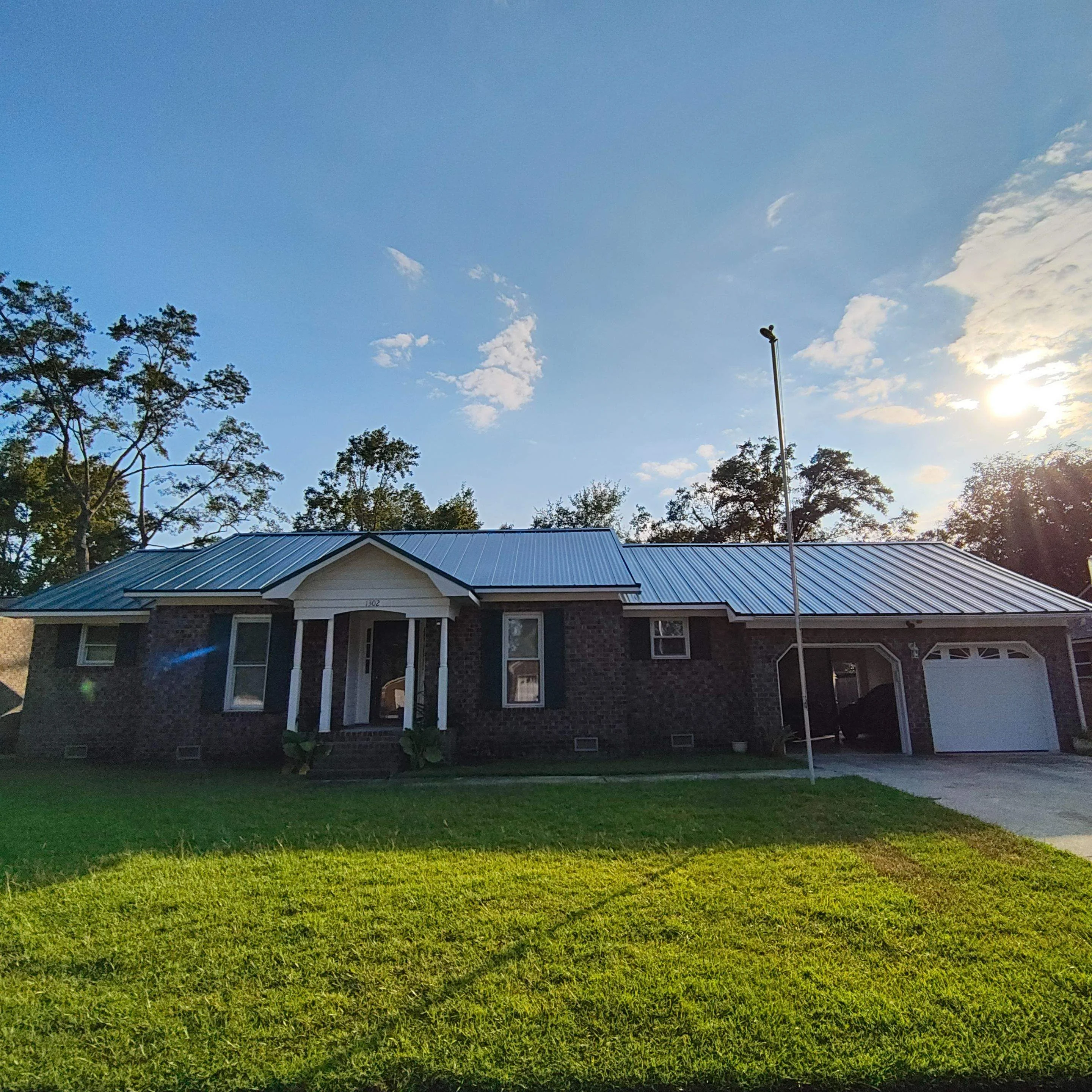 Standing seam metal roof on brick ranch home with garage, blue-gray finish