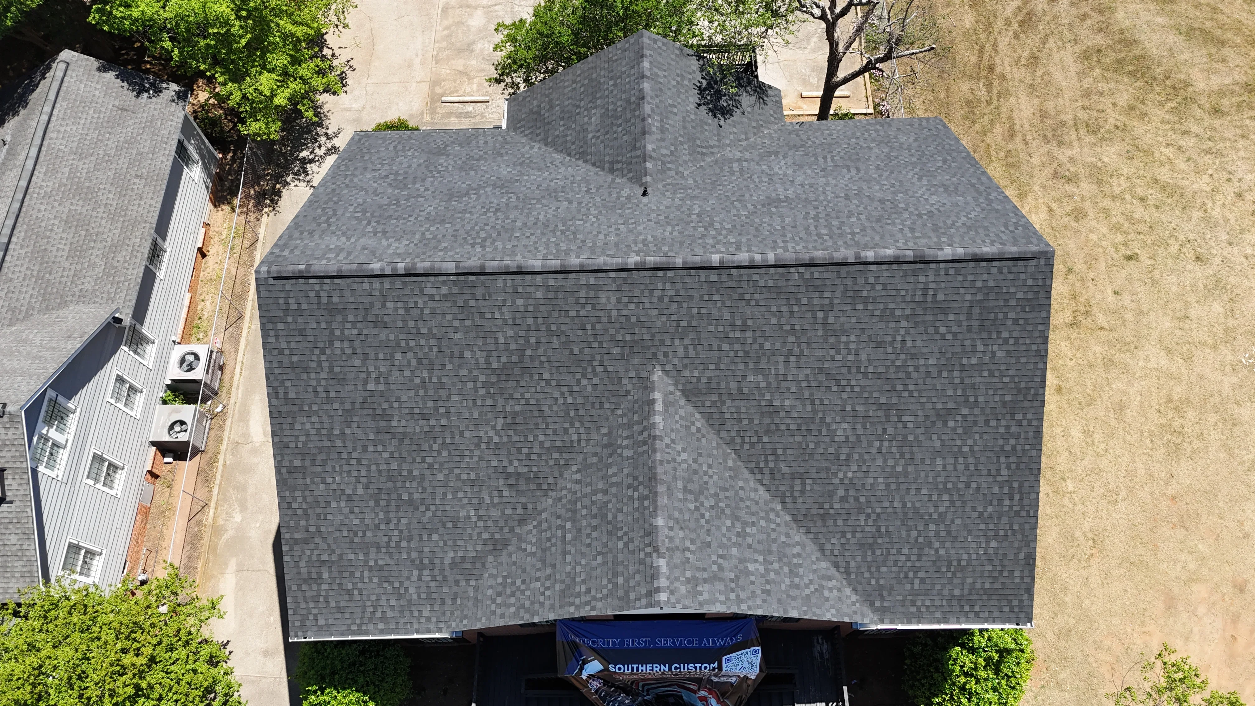 Aerial view of completed asphalt shingle roof with charcoal gray architectural shingles on multi-pitched residential home
